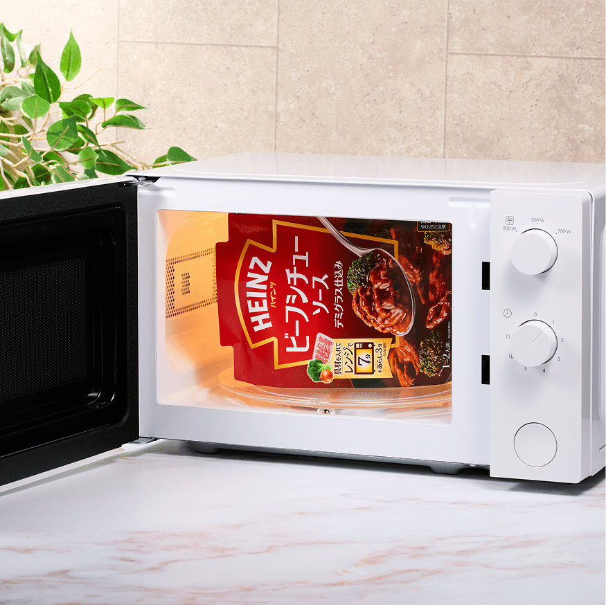 扉が開いた白い電子レンジの中に、自立して置かれたハインツのビーフシチューソースの袋。