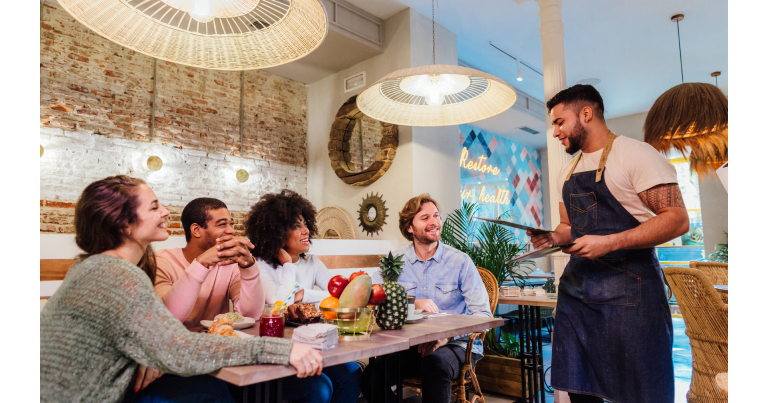 A waiter presents a menu to a group of people at a restaurant.