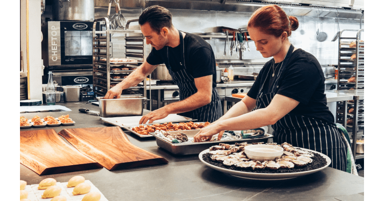 Chefs preparing food in a commercial kitchen.
