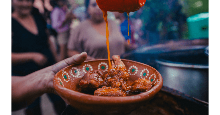 Sauce is poured onto a plate of meat.