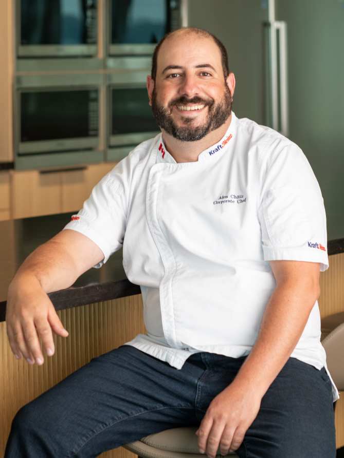 A photo of a chef in a white jacket sitting on a chair.