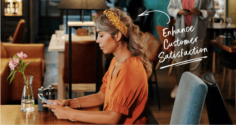 A woman looks at her phone in a cafe that says "Enhance Customer Satisfaction."