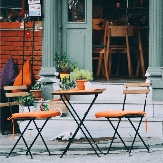 Table et deux chaises devant un café avec un chat endormi.