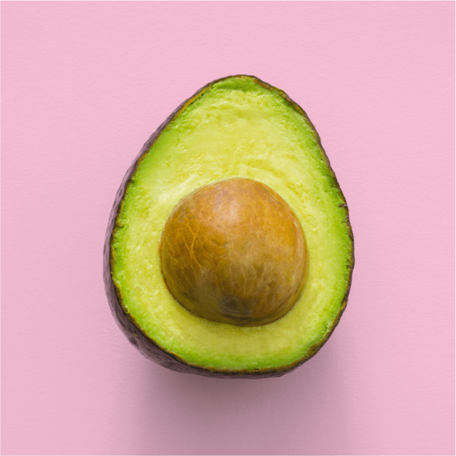 Half avocado with seed on a pink background