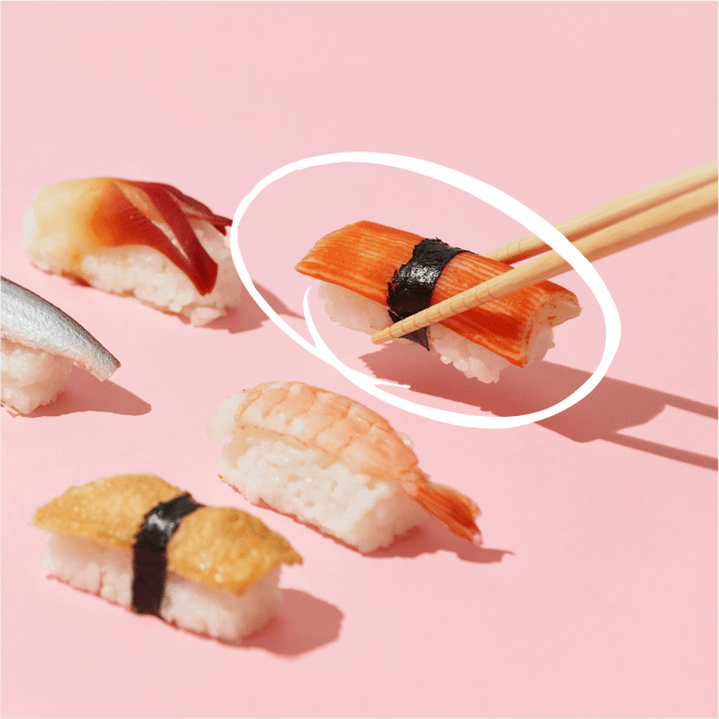 Sushi au crabe avec des baguettes sur fond rose