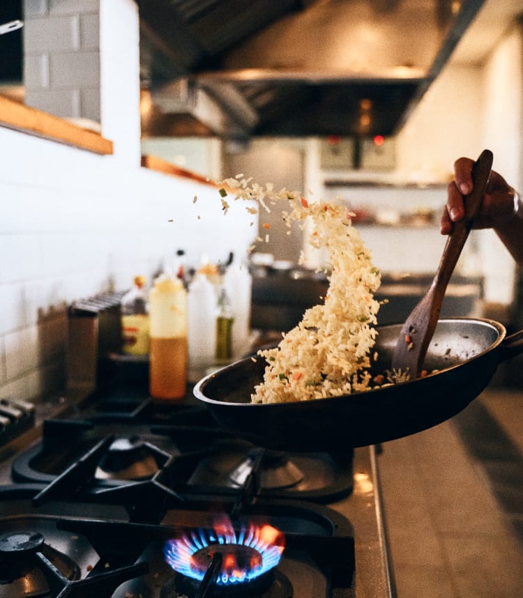 Fried rice being tossed in a frying pan