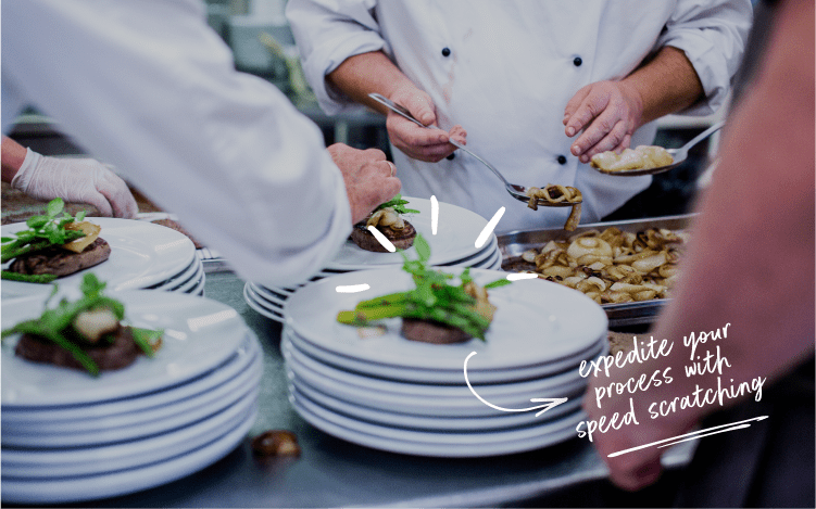 Chefs plating meat dishes with vegetables.