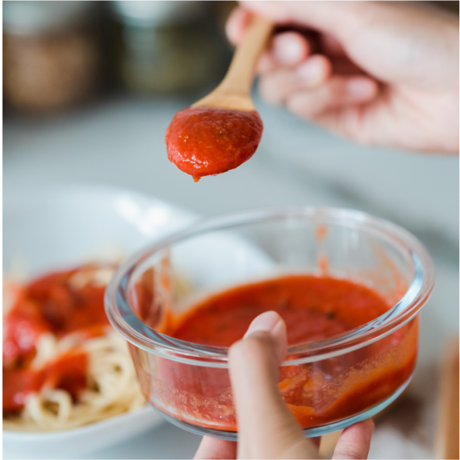 Sauce tomate sur une cuillère au-dessus d'un bol de sauce.