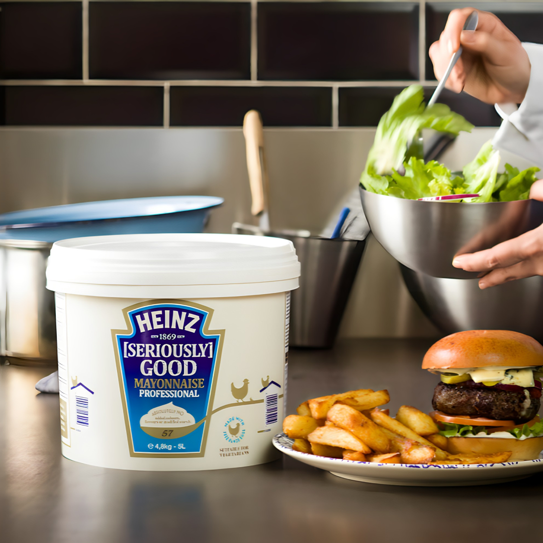 A tub of Heinz mayonnaise next to a salad and burger.