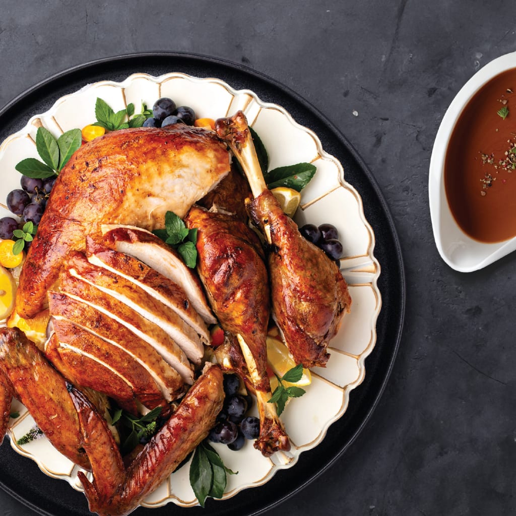 A top down shot of gravy-covered meat on a platter next to a gravy boat.