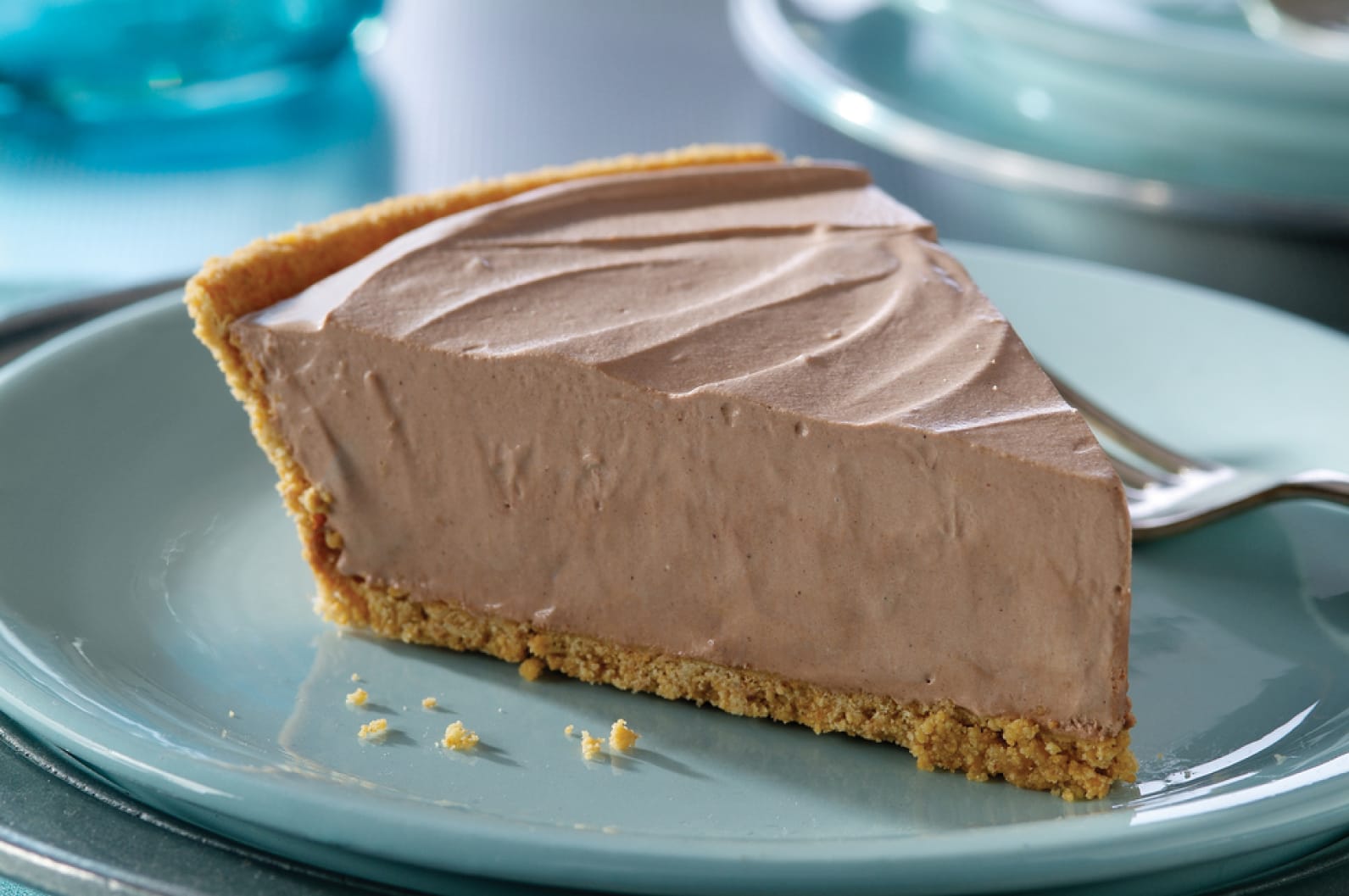 A slice of chilled, creamy chocolate pie in a graham cracker crust on a blue plate.