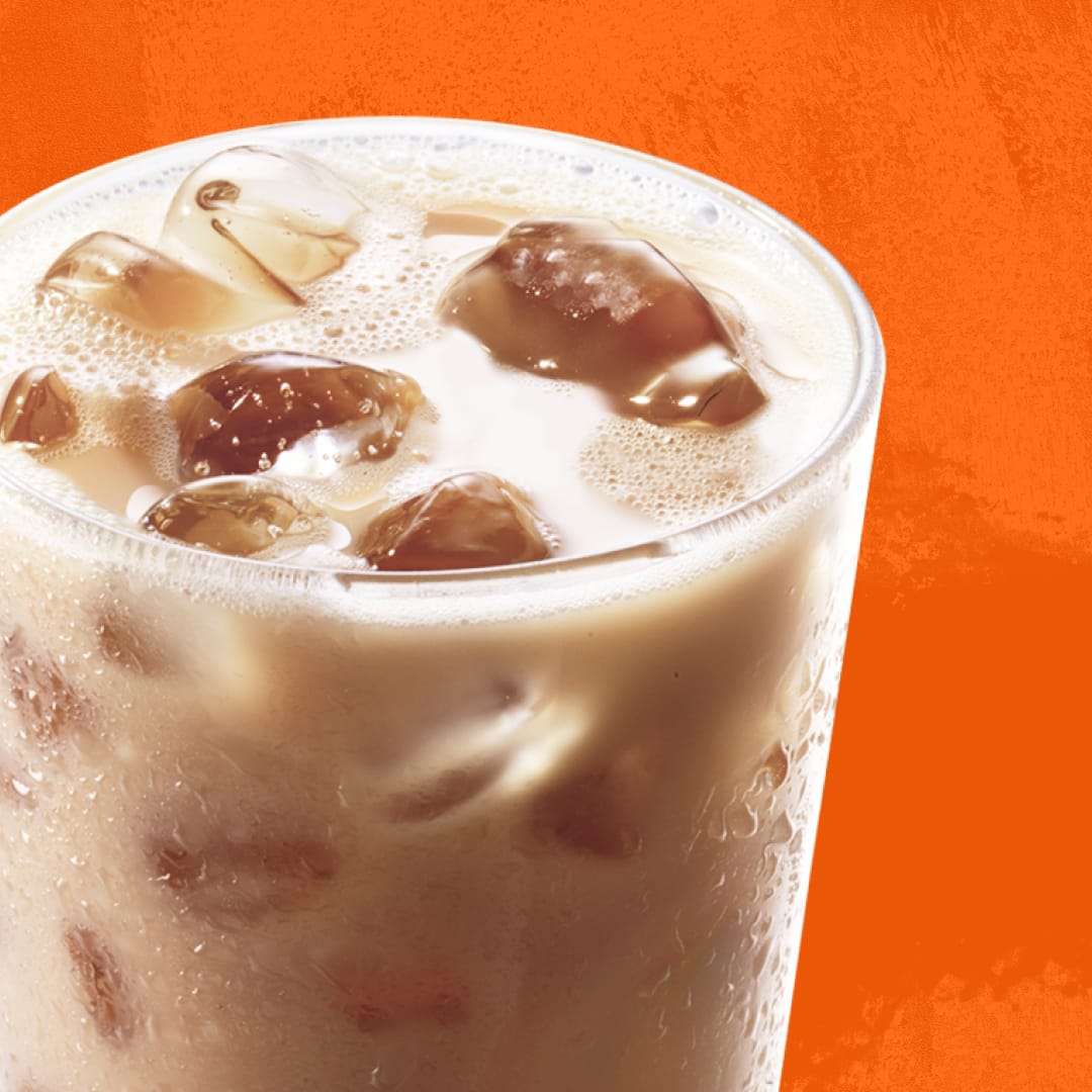 A glass of coffee latte with ice on an orange background