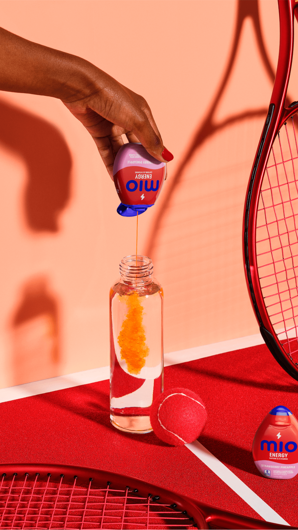 Hand pouring Mio Energy into water bottle next to tennis gear.