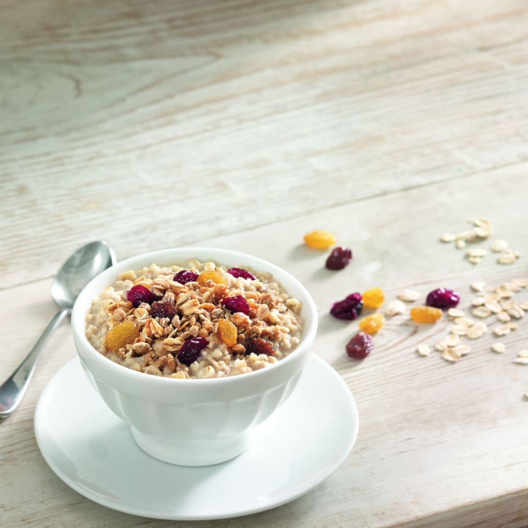 Een kom ontbijtgranen gegarneerd met gedroogd fruit.