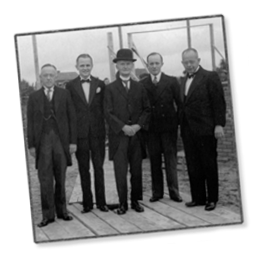 Een historische foto van vijf mannen in pak.