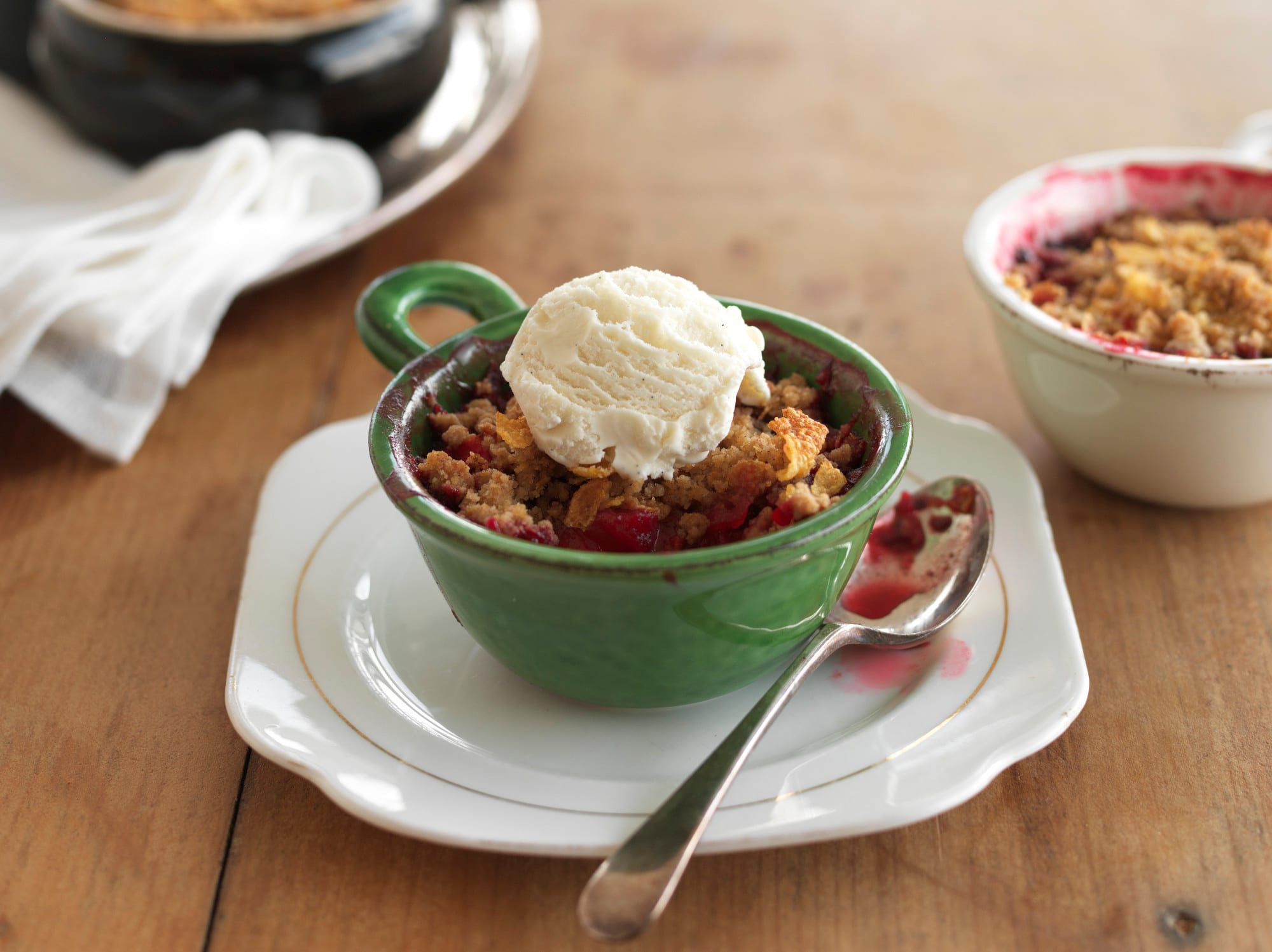Fruit crumble with ice cream in a green bowl.