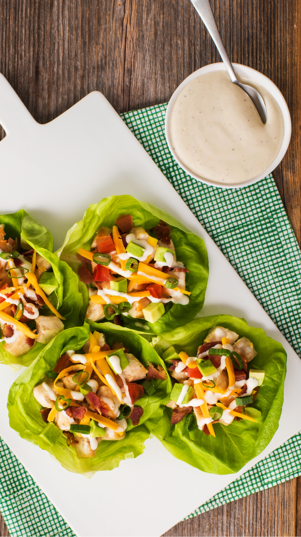 Bouchées de laitue avec poulet, bacon, fromage, avocat et vinaigrette sur un plateau blanc.