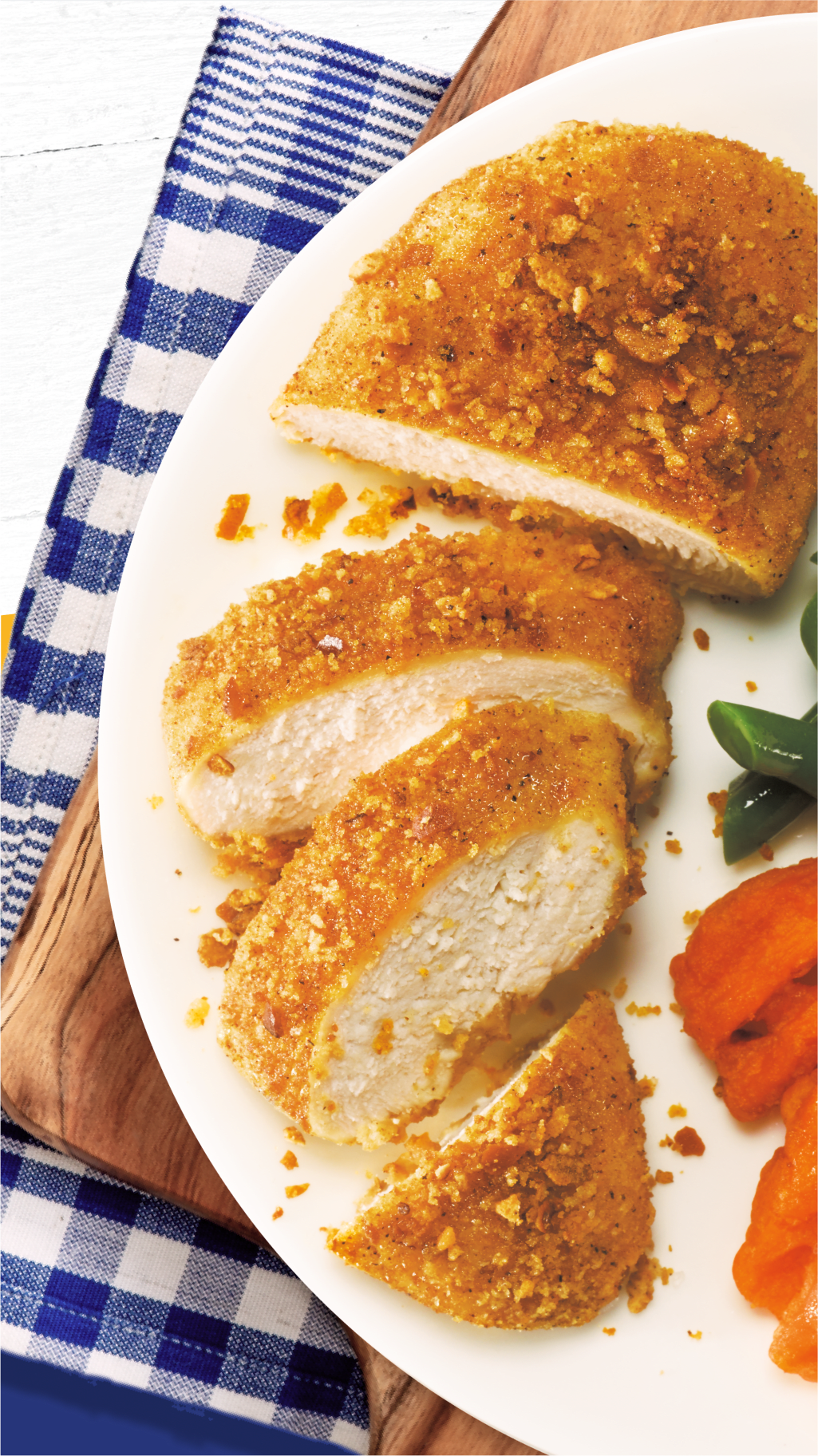 Sliced breaded chicken with green beans, sweet potatoes, and a bowl of sauce.
