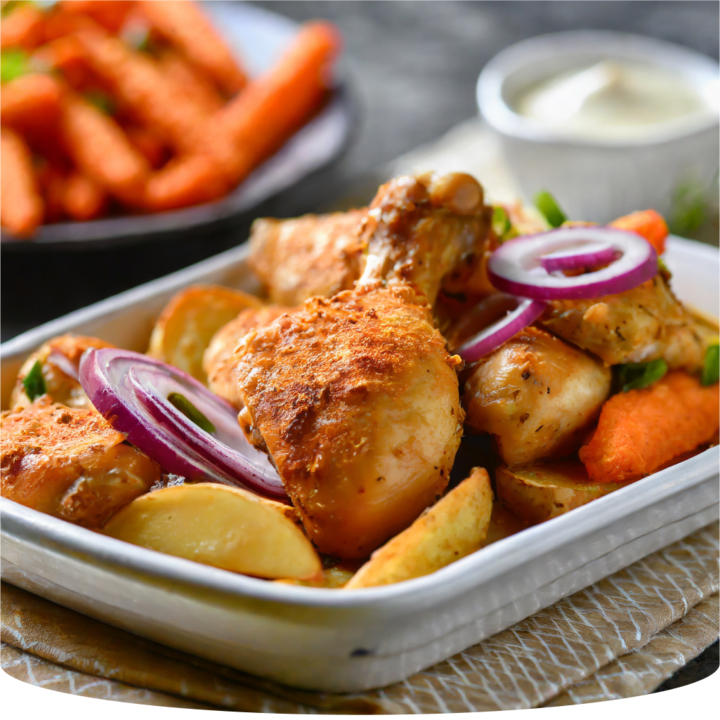 Dish of chicken, potatoes, carrots and onion rings.