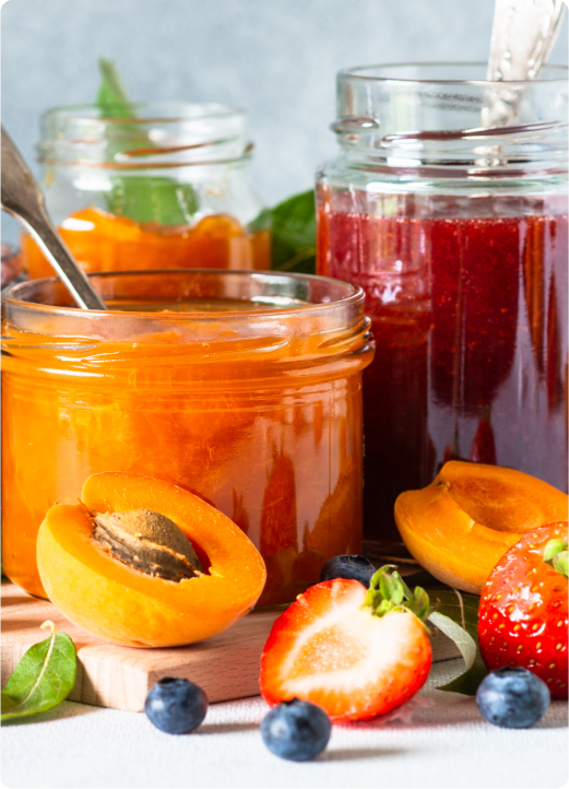 A still life image of various jams and fruits.