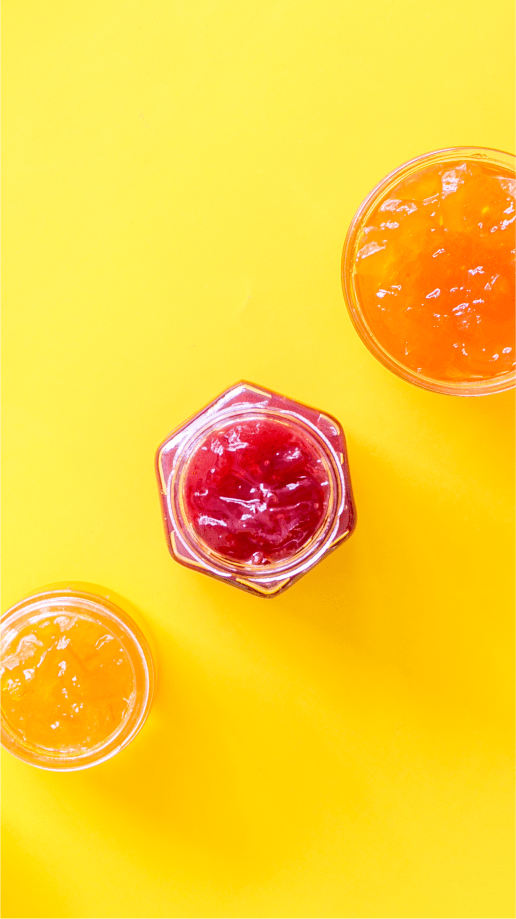 Various jam jars with orange and red jams in them