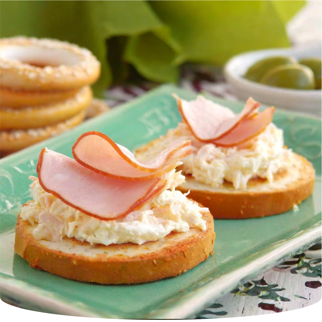 Snacks with cream cheese and ham on a green plate.