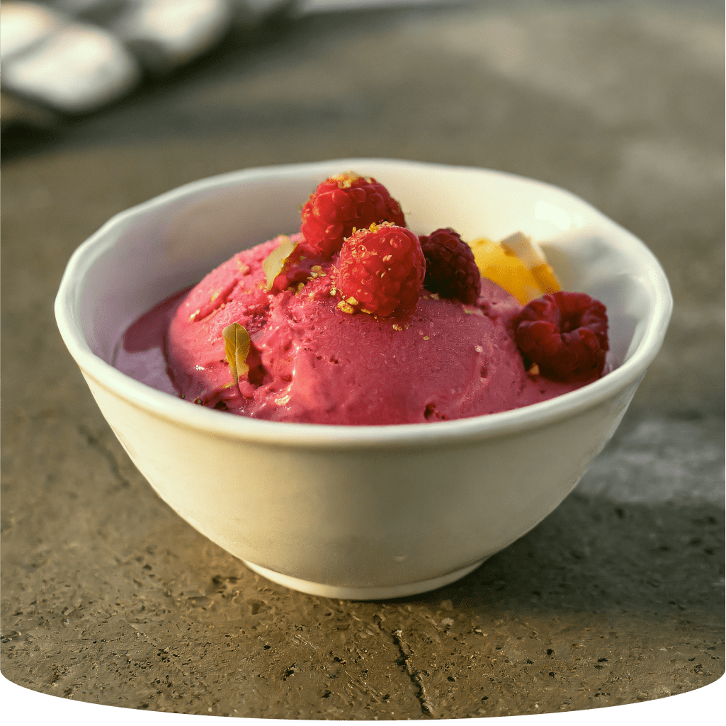Raspberry sorbet in a bowl with fresh raspberries.