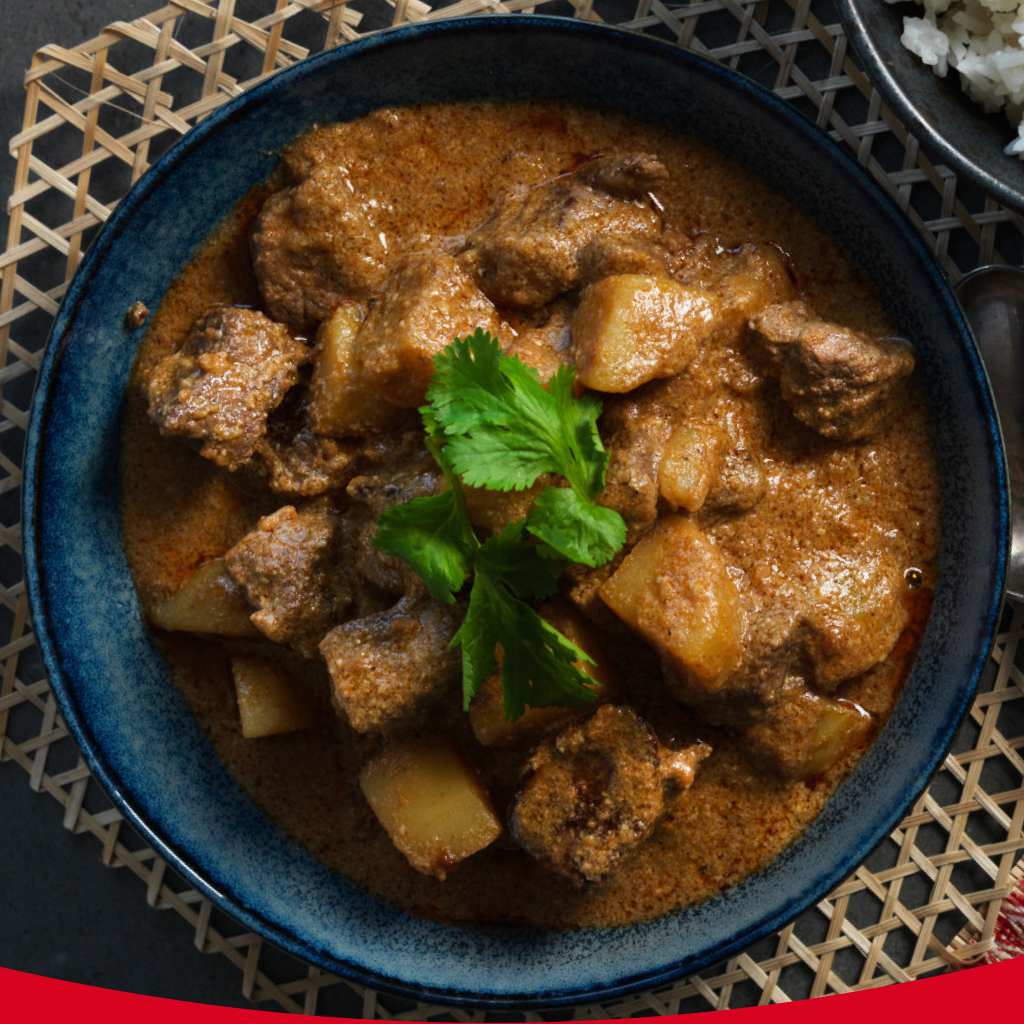 A bowl of stew in a blue bowl garnished with parsley.
