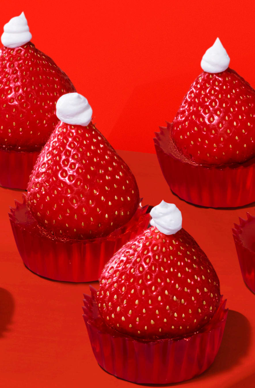 Strawberry tops with whipped cream in red paper cups.