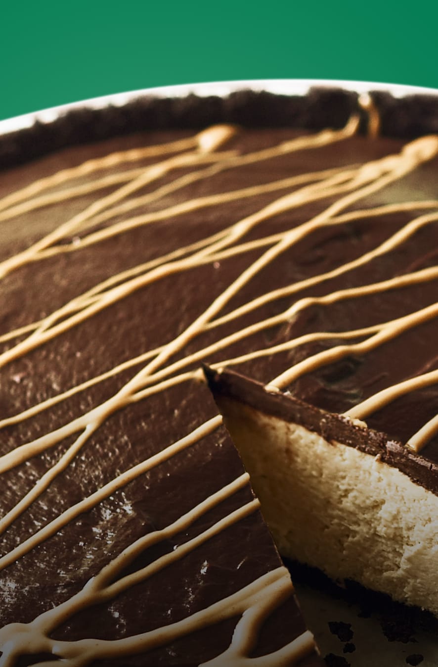 Chocolate pie with caramel drizzle and white filling on a green background.