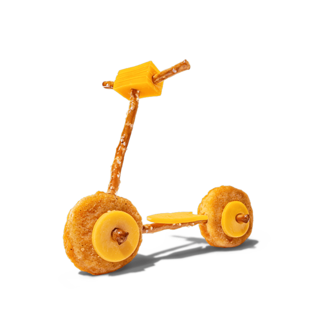 A scooter made of chicken nuggets, pretzels, and cheese on a black background.