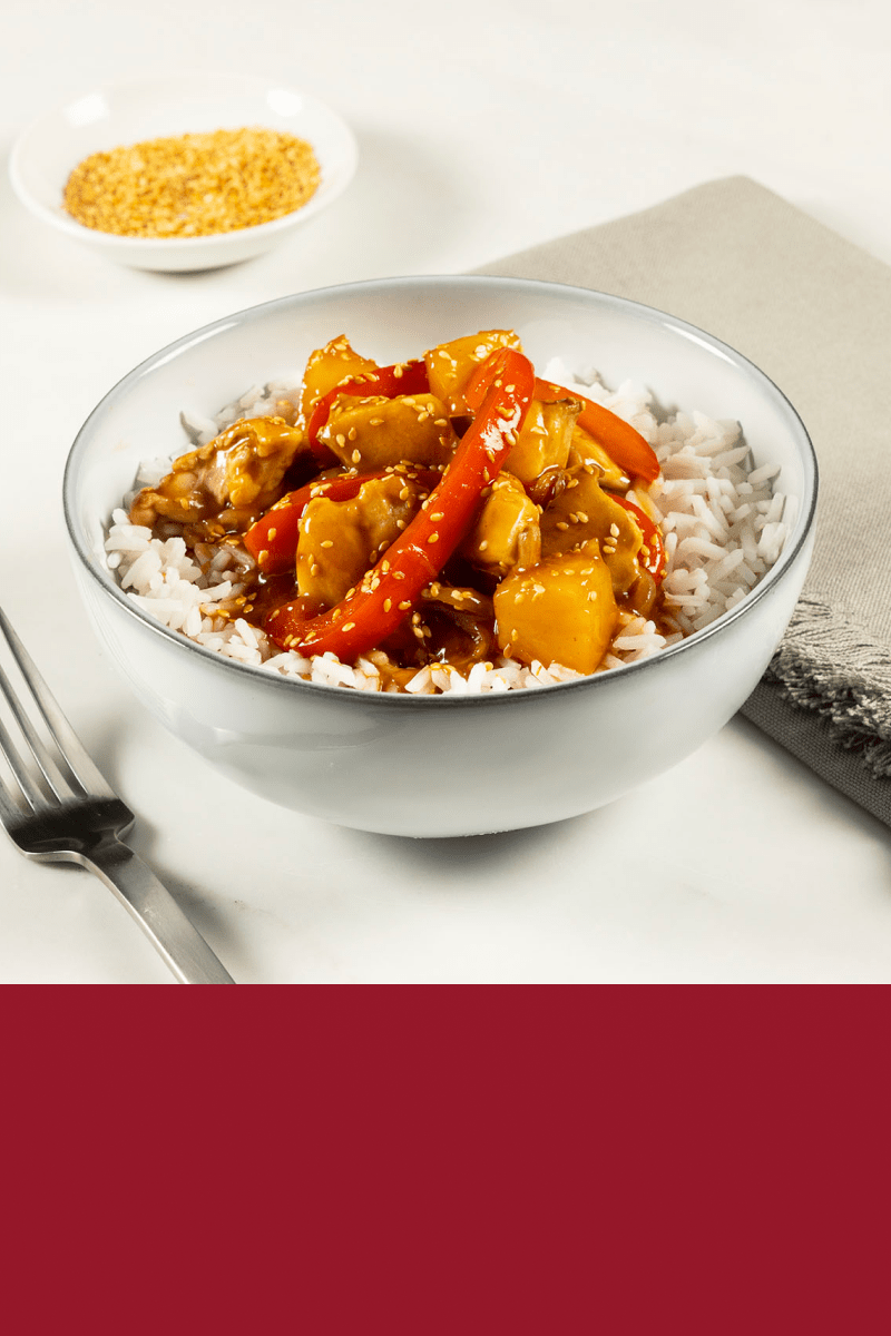 A bowl filled with rice and Sweet & Sour Chicken made with HEINZ HomeStyle Brown Gravy.