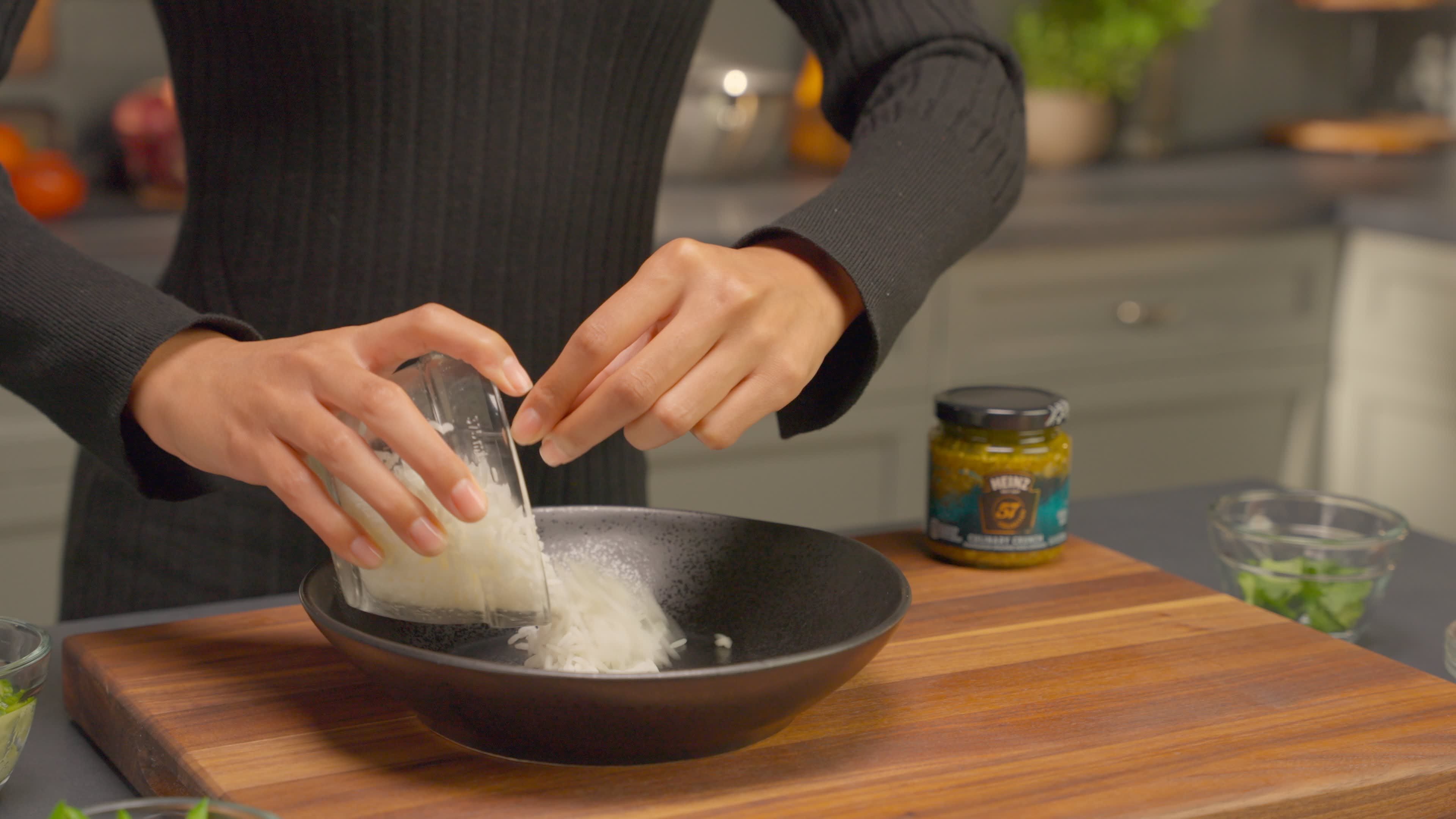 Hot cooked rice is spooned into a large, shallow serving bowl.
