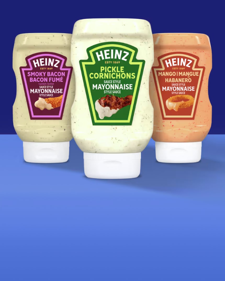 Three bottles of Heinz mayonnaise-style sauces: Smoky Bacon, Pickle, and Mango Habanero, against a blue background.