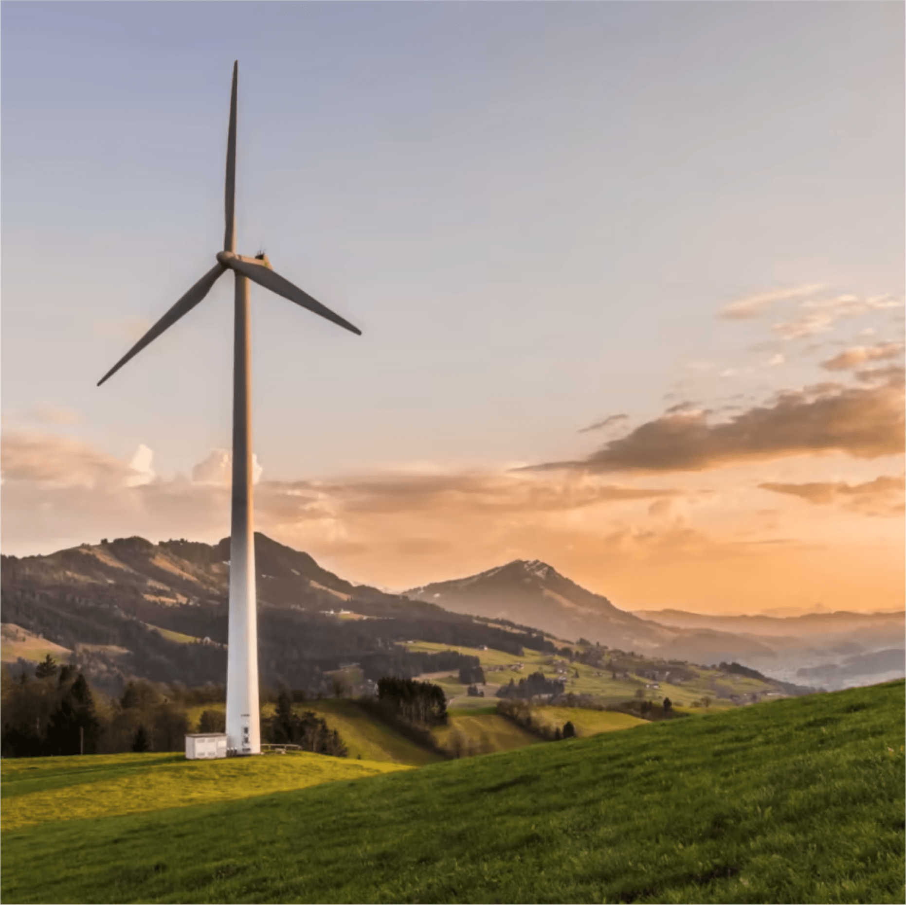 A tall wind turbine stands in a green field, its white blades reaching towards the sky. The background reveals a picturesque 