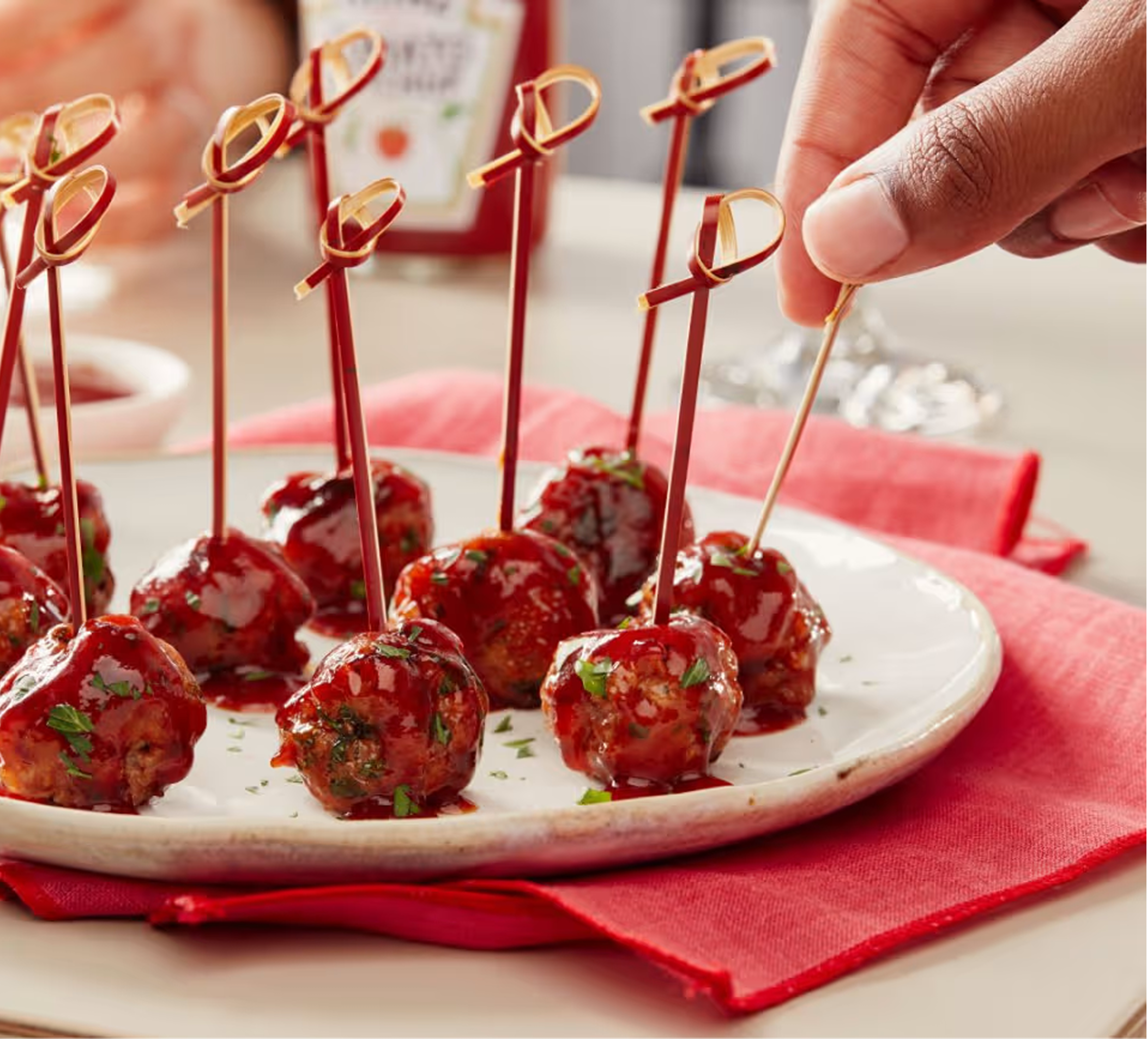 Köttbullar med cocktailspett garnerade med persilja med en flaska Heinz Ketchup i bakgrunden.