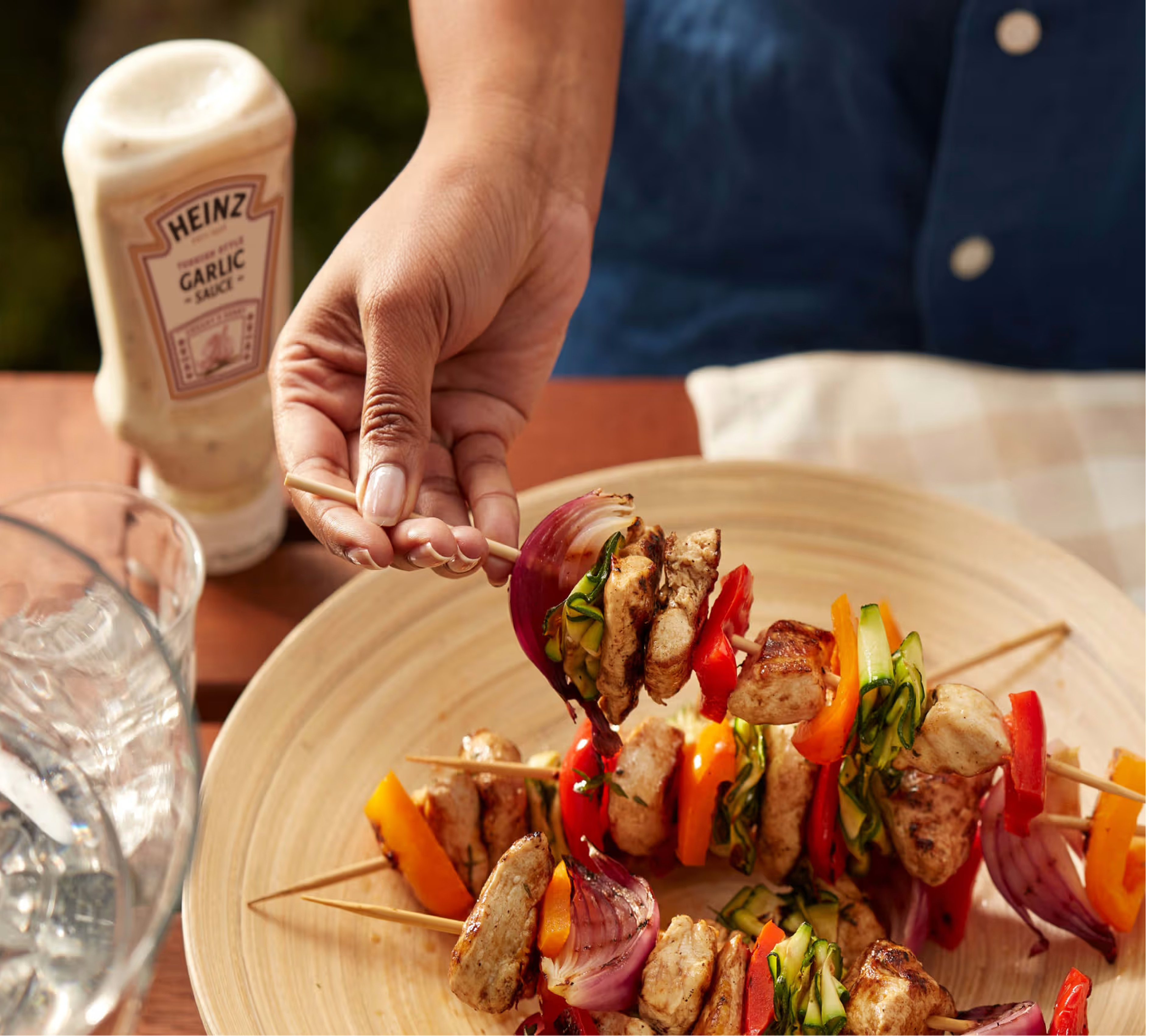 Lautasellinen liha- ja kasvisvartaita ja pullo Heinz-valkosipulikastiketta.