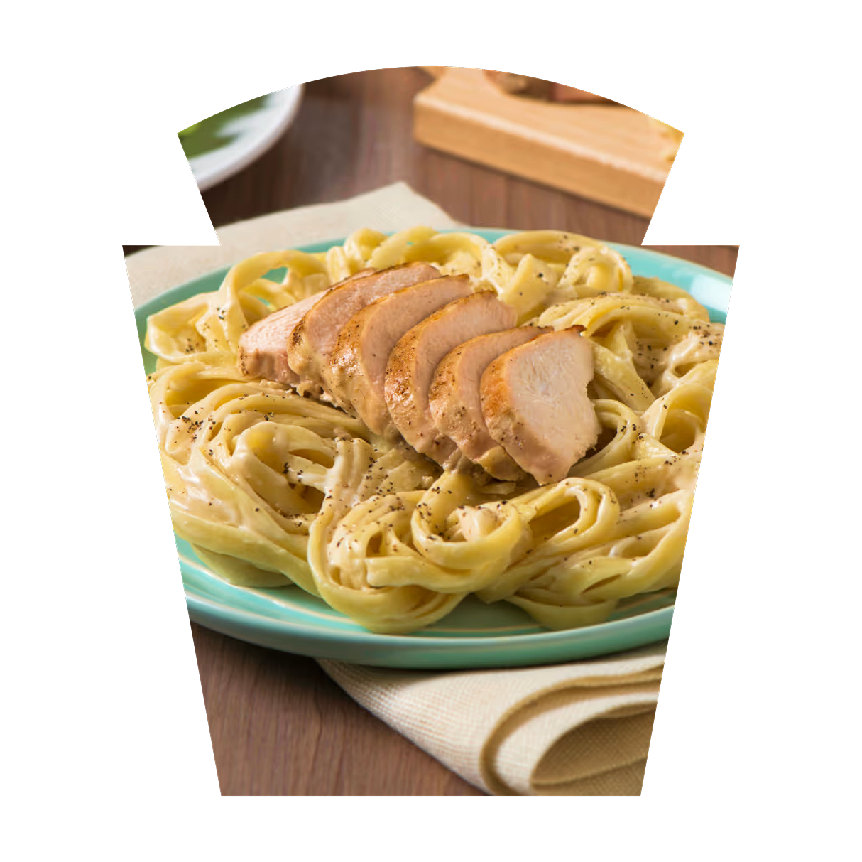 Creamy fettuccine pasta with sliced grilled chicken on a blue plate.