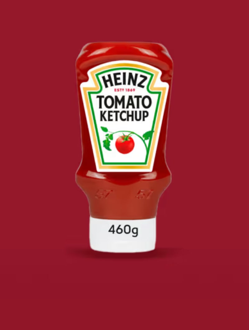 A red Heinz Tomato Ketchup bottle with a red tomato on its label, shown against a red background.