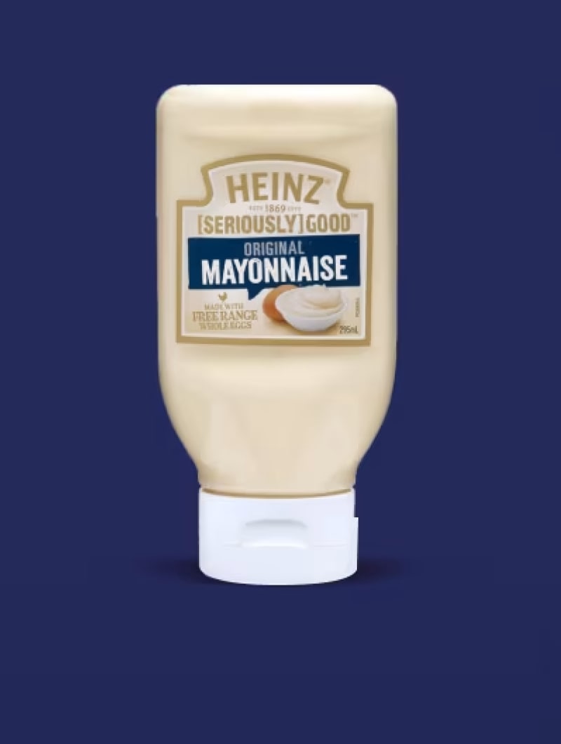 A white squeeze bottle of Heinz [Seriously] Good Original Mayonnaise against a dark blue background.