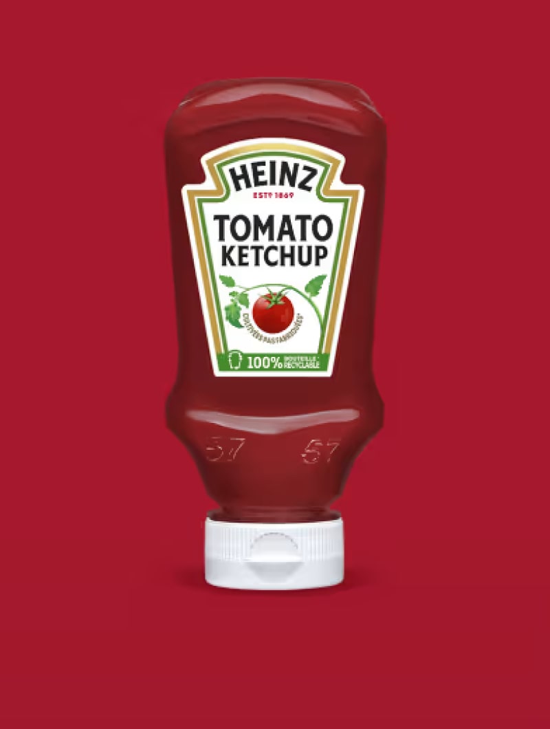 Une bouteille de ketchup Heinz avec un bouchon blanc. Sur l'étiquette, on peut lire "HEINZ ESTD 1869 TOMATO KETCHUP" avec une