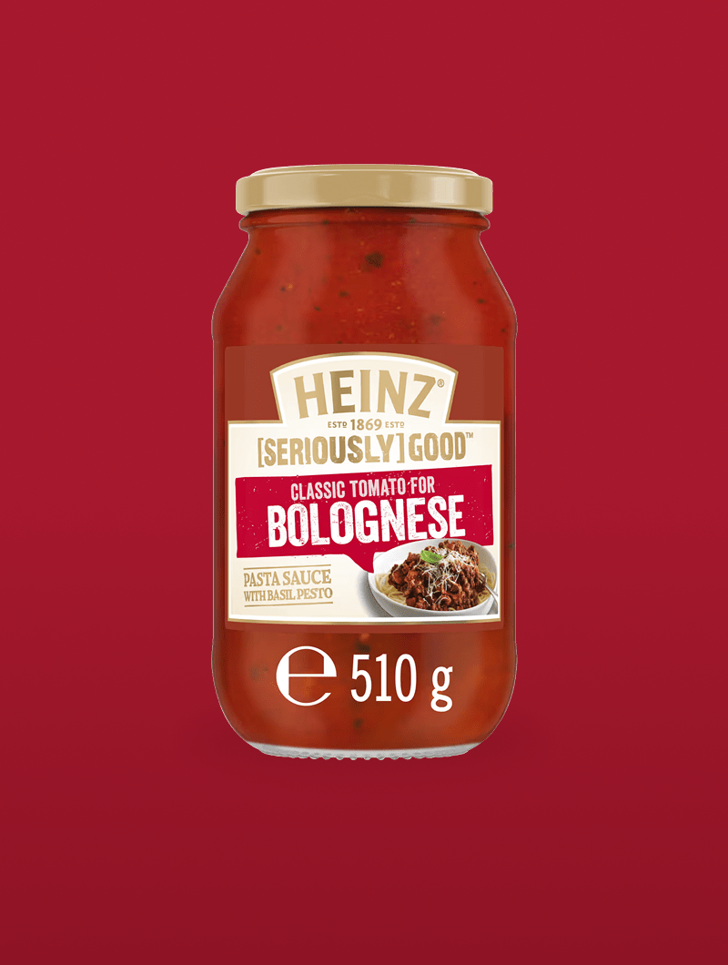A glass jar of Heinz [Seriously] Good Pasta Sauce Classic Tomato for Bolognese, against a deep red background.