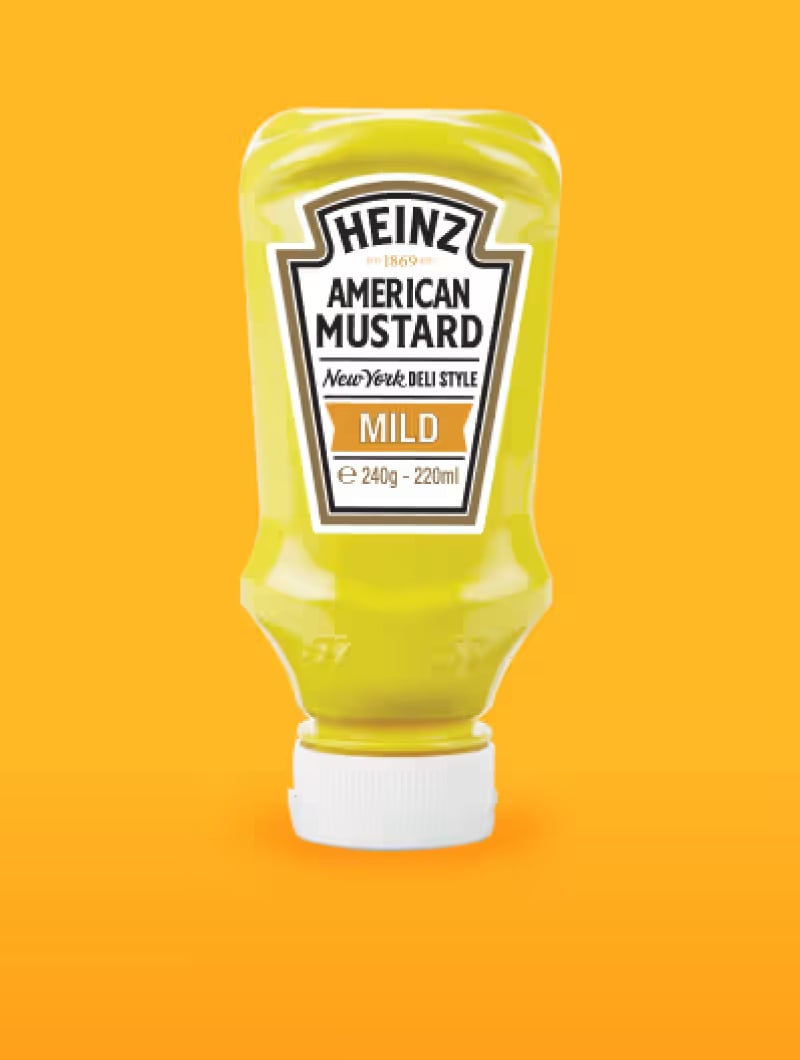 Uma garrafa invertida de Mostarda Americana Heinz, Estilo Deli de Nova Iorque, está centrada contra um fundo laranja