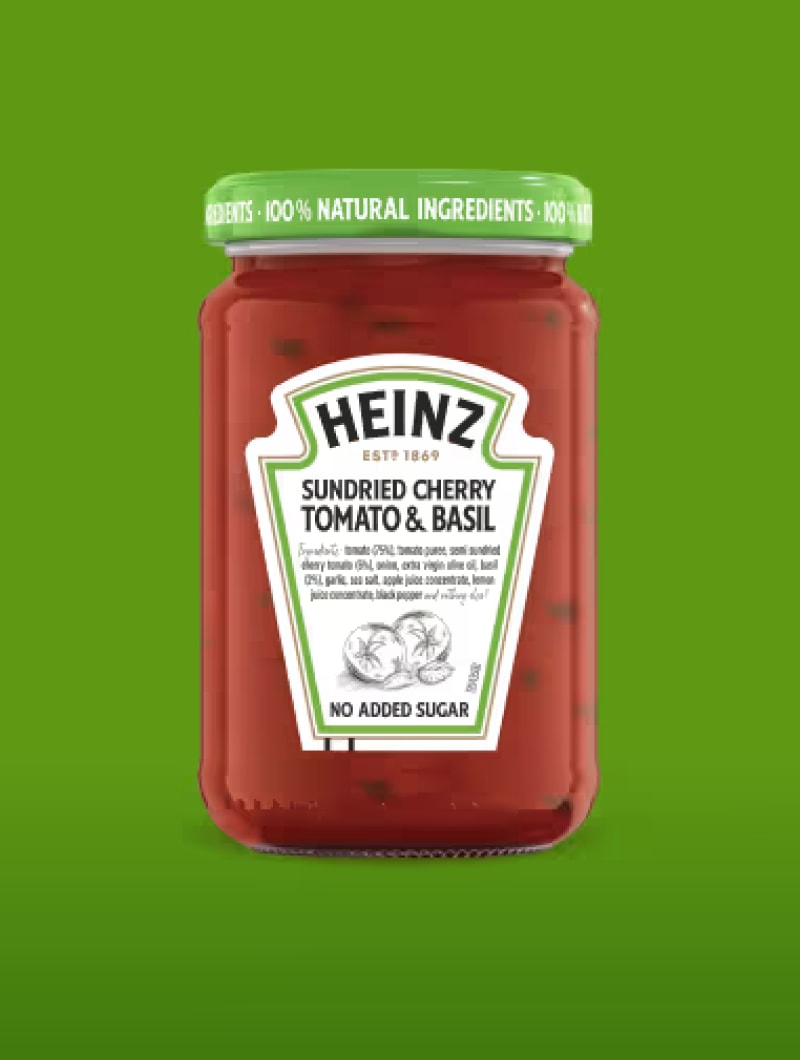 A glass jar of Heinz Sundried Cherry Tomato & Basil sauce, with "No Added Sugar" highlighted, against a green background.