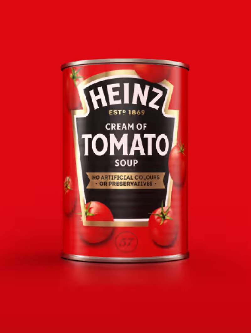 A red can of Heinz Cream of Tomato Soup, with illustrations of tomatoes on its label, against a bright red background.