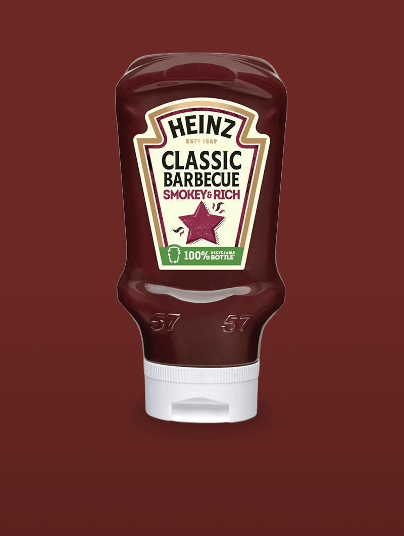 Una botella de salsa Heinz Classic Barbecue Smokey & Rich con tapón blanco, sobre un fondo granate liso. La etiqueta muestra 