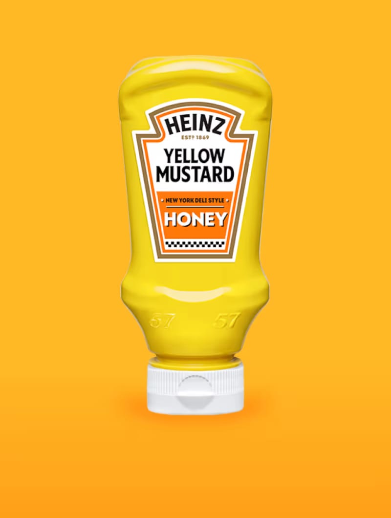 Odwrócona butelka typu squeeze Musztardy Żółtej Heinz, New York Deli Style, odmiana Miodowa, jest wyśrodkowana na jednolitym