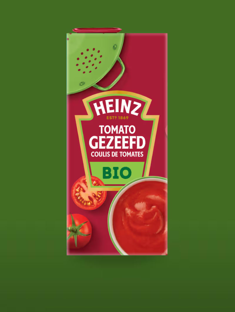 Een pak Heinz Tomato Gezeefd Bio (biologische gezeefde tomaten). Op het etiket staat "HEINZ ESTD 1869 TOMATO GEZEEFD COULIS D
