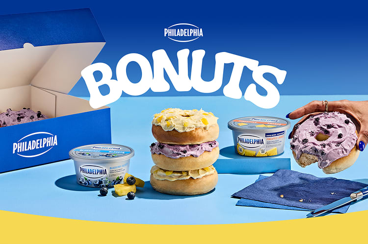 An array of bagels filled with Philadelphia cream cheese in blueberry and pineapple flavors, arranged on a light blue surface