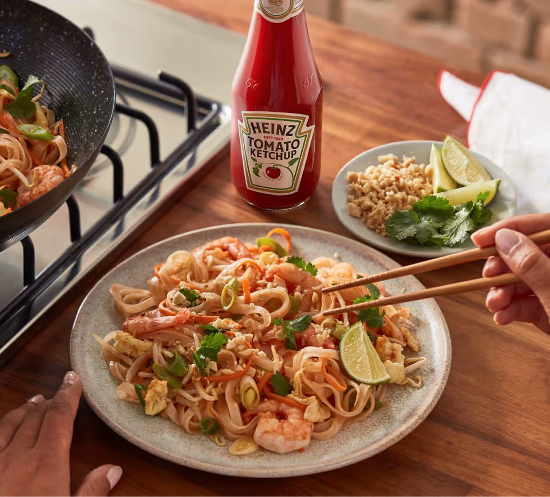 Image de bannière montrant une assiette de Pad Thaï aux crevettes à côté d'une bouteille de Ketchup Tomate Heinz.